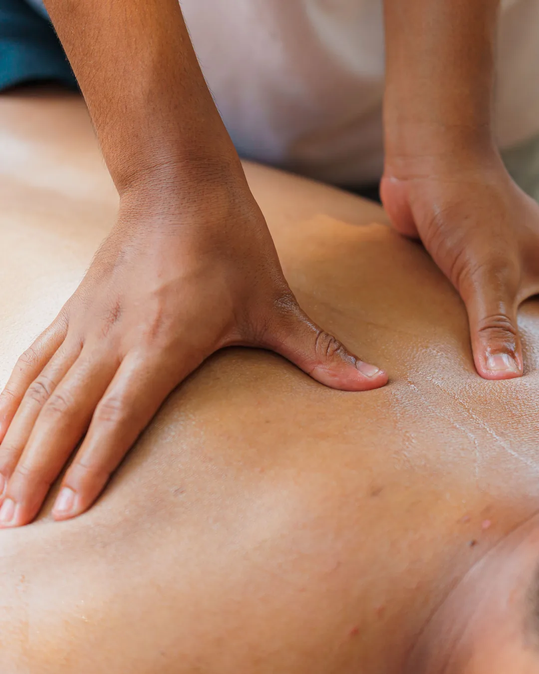 Gros plan sur les mains d'un praticien pendant un massage du dos