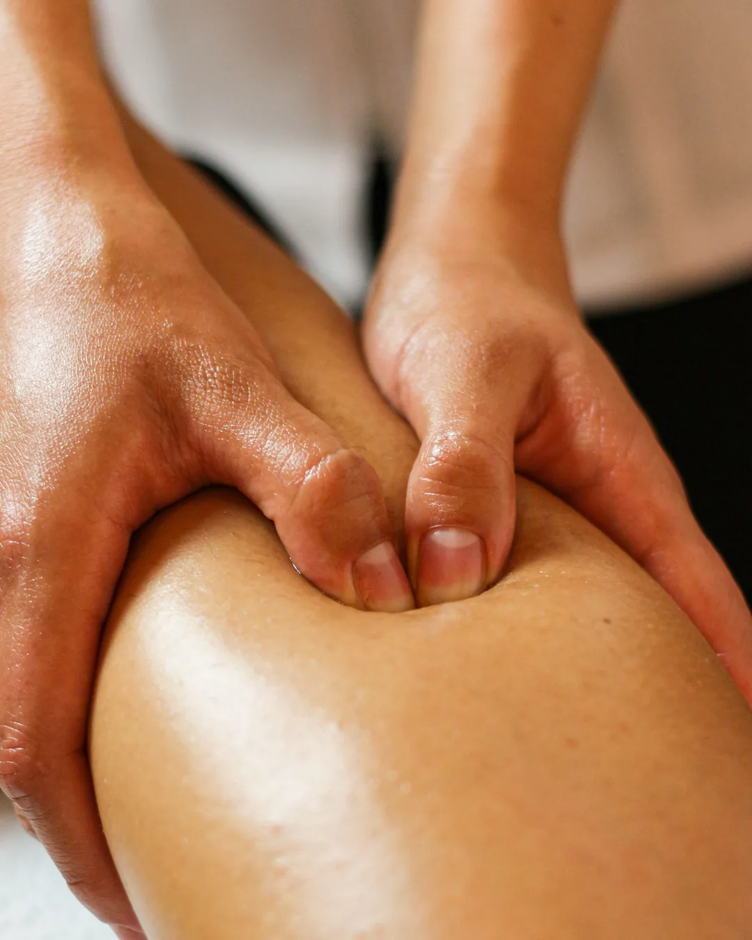 Gros plan sur les mains d'un praticien pendant un massage sportif de la cuisse